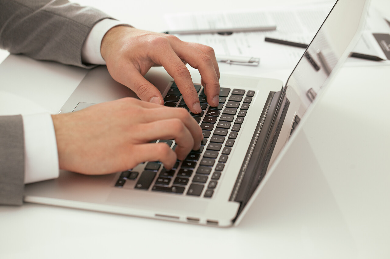 在笔记本电脑键盘上打字的商人的手的特写镜头