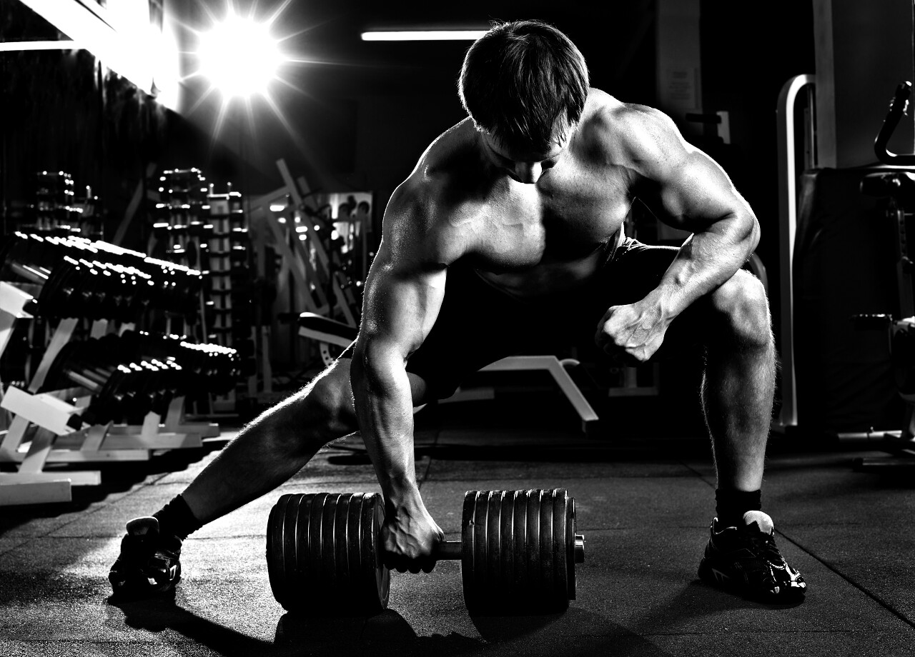 运动的家伙与哑铃牵引黑白照片