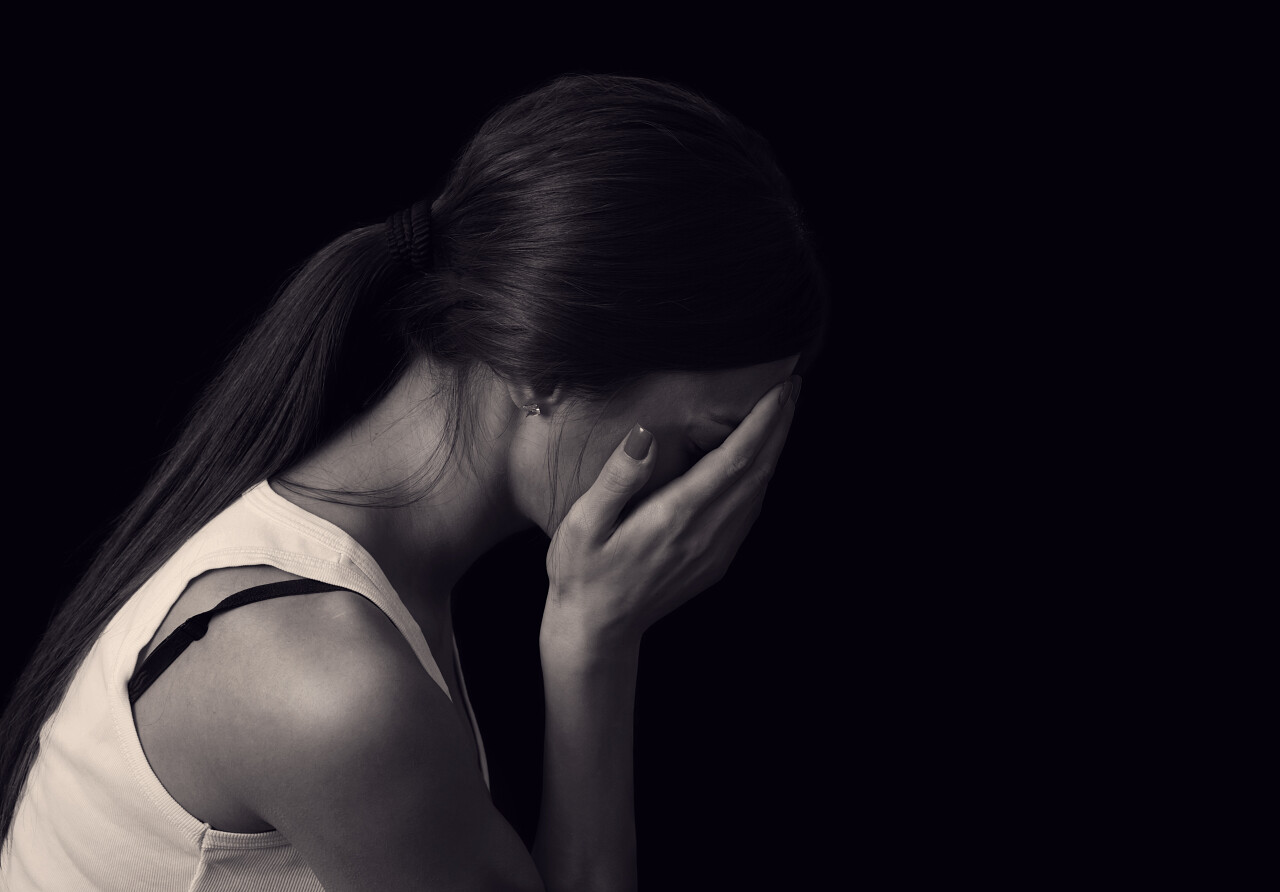年轻女性表达在黑色背景上的痛苦和悲伤
