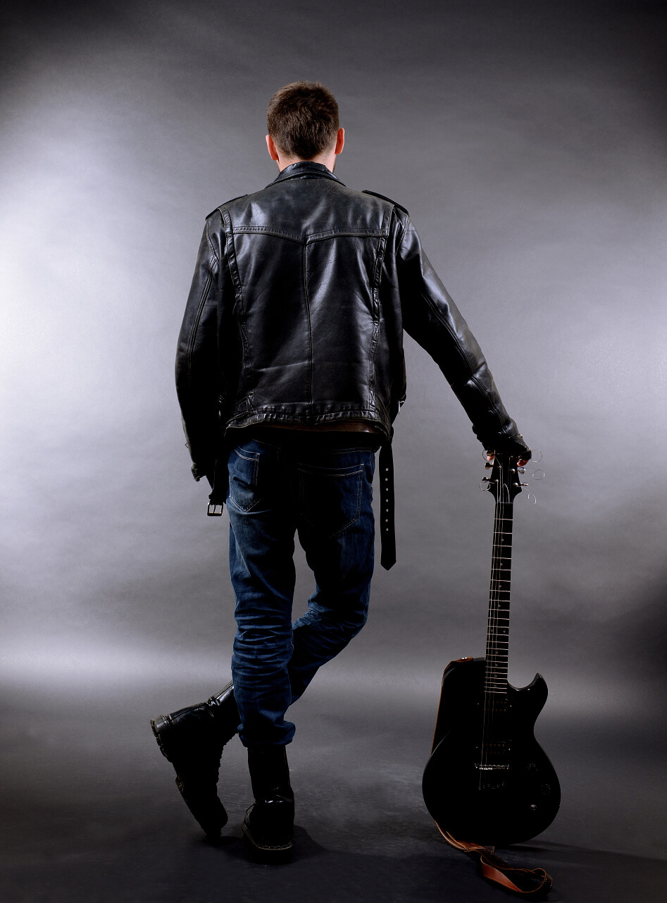 年轻的音乐家在深色背景上的吉他