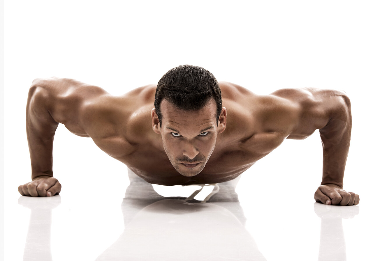 肌肉健壮的男子俯卧撑在画室被隔绝在一个白色的背景