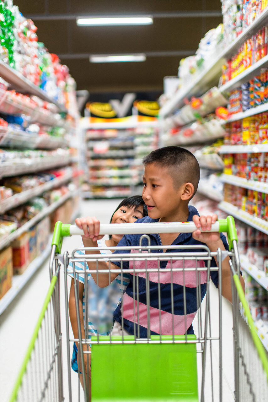 微笑的男孩和他的妹妹在超市购物