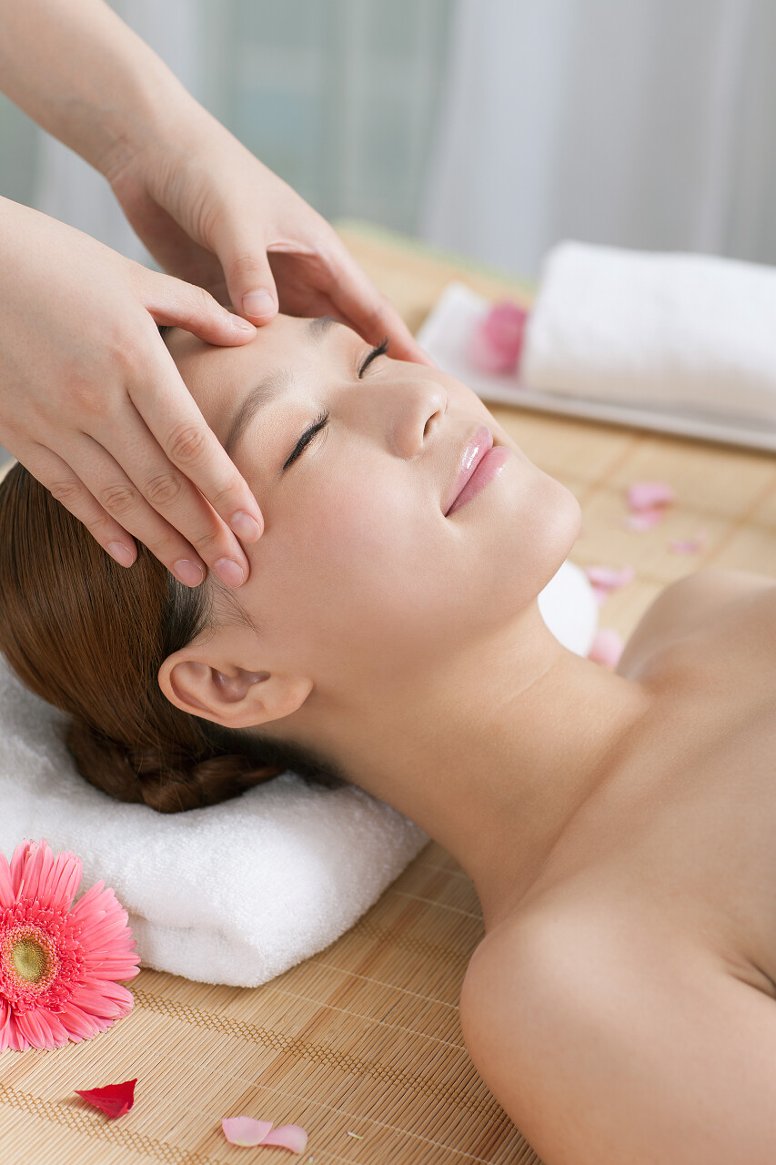 一个年轻漂亮的女人正在享受面部按摩放松解压面部清洁脸部中医养生头部按摩