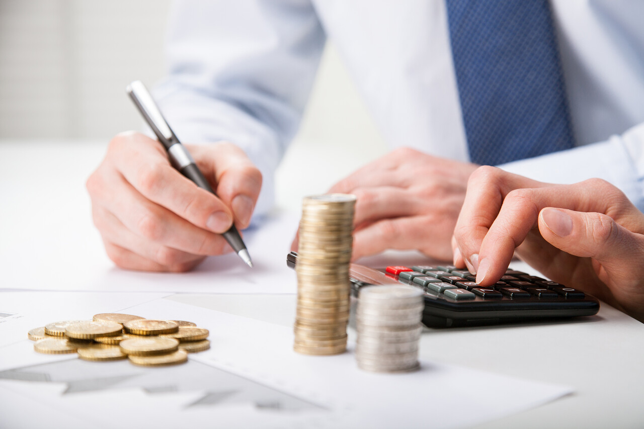 会计师计算利润-计数硬币和在纸上做笔记的手的特写镜头