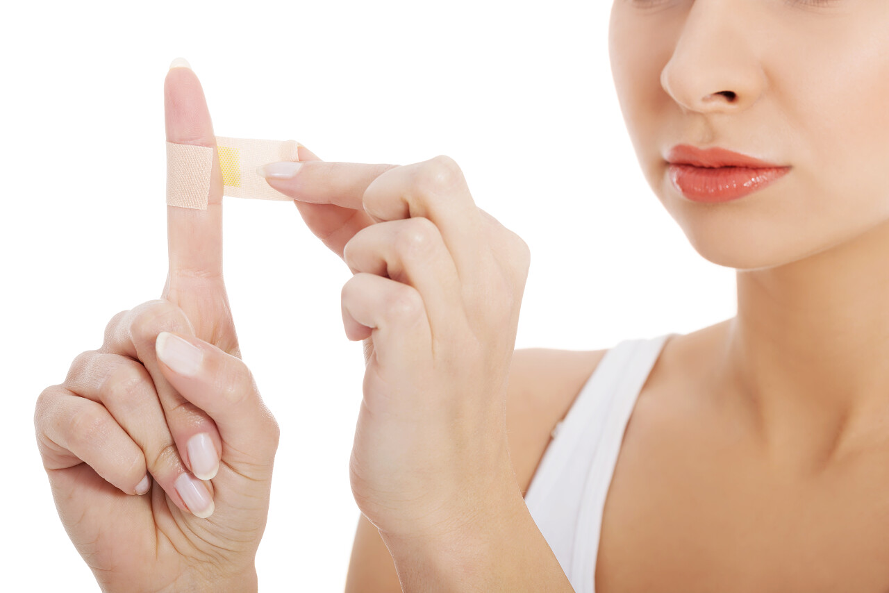 美丽的女人她的手指上把胶带缠在她的手指上