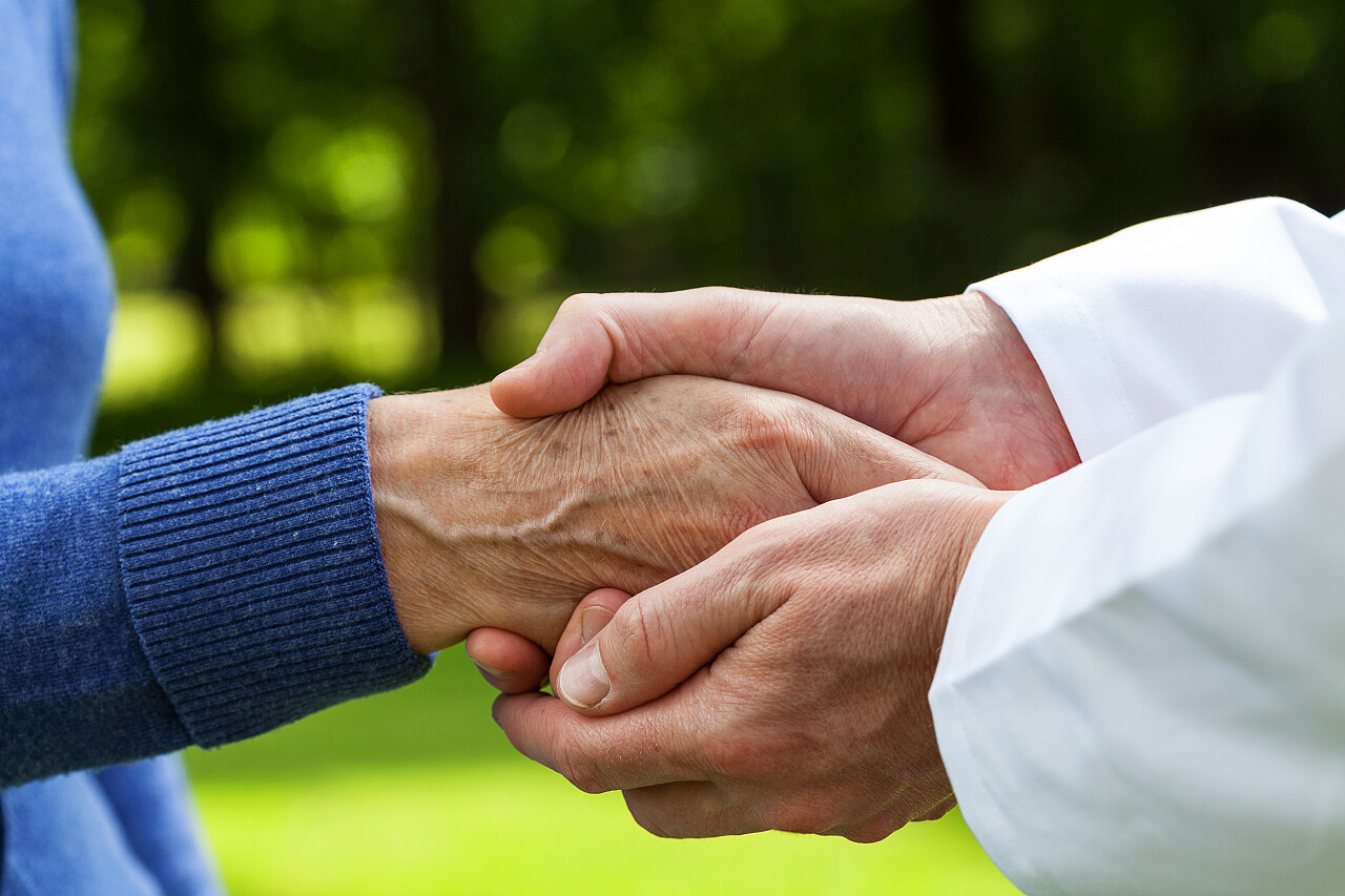 一名医生关爱的握着一名病人的手救命