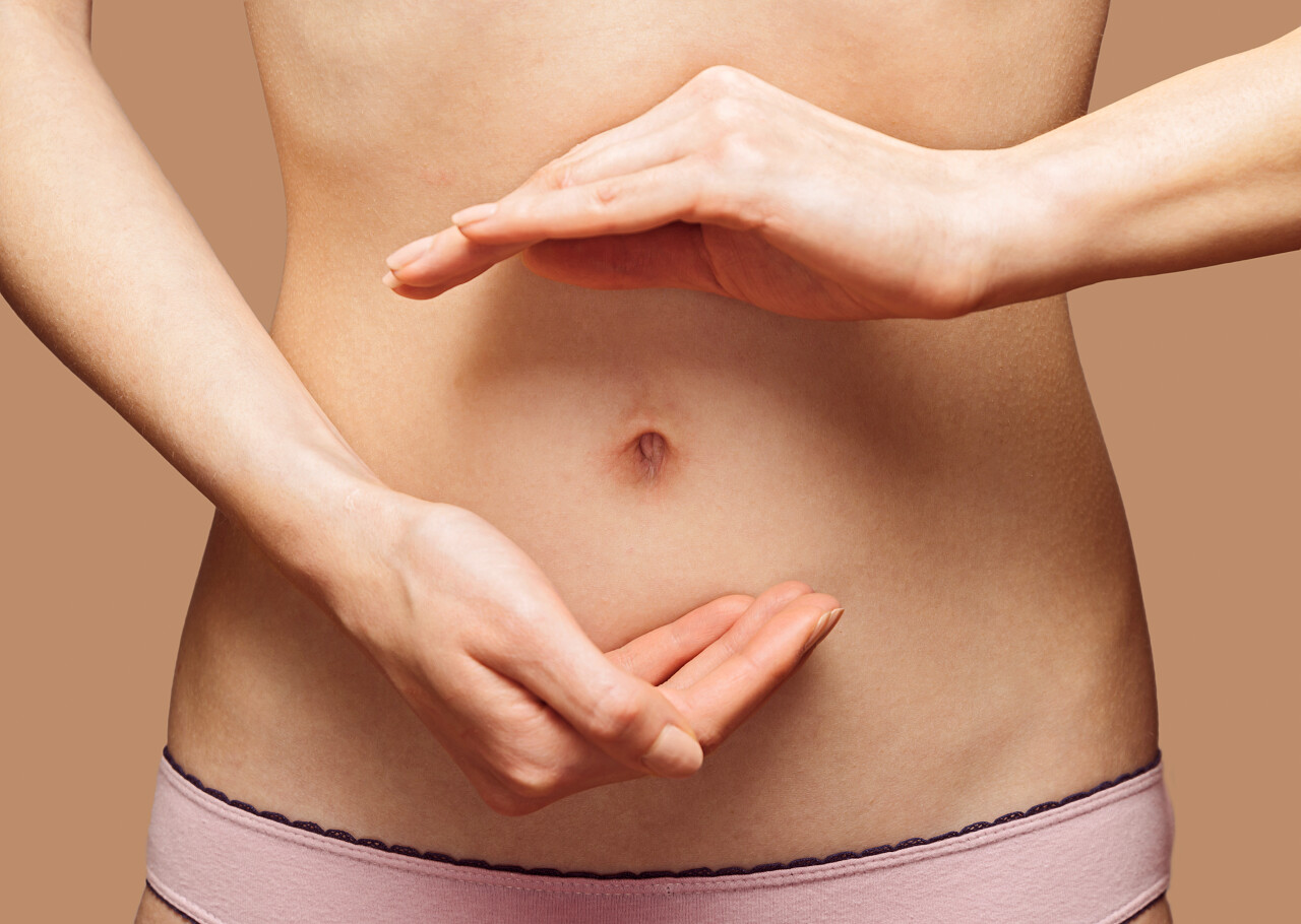 在她的腹部女人的手抱成圆圈形状