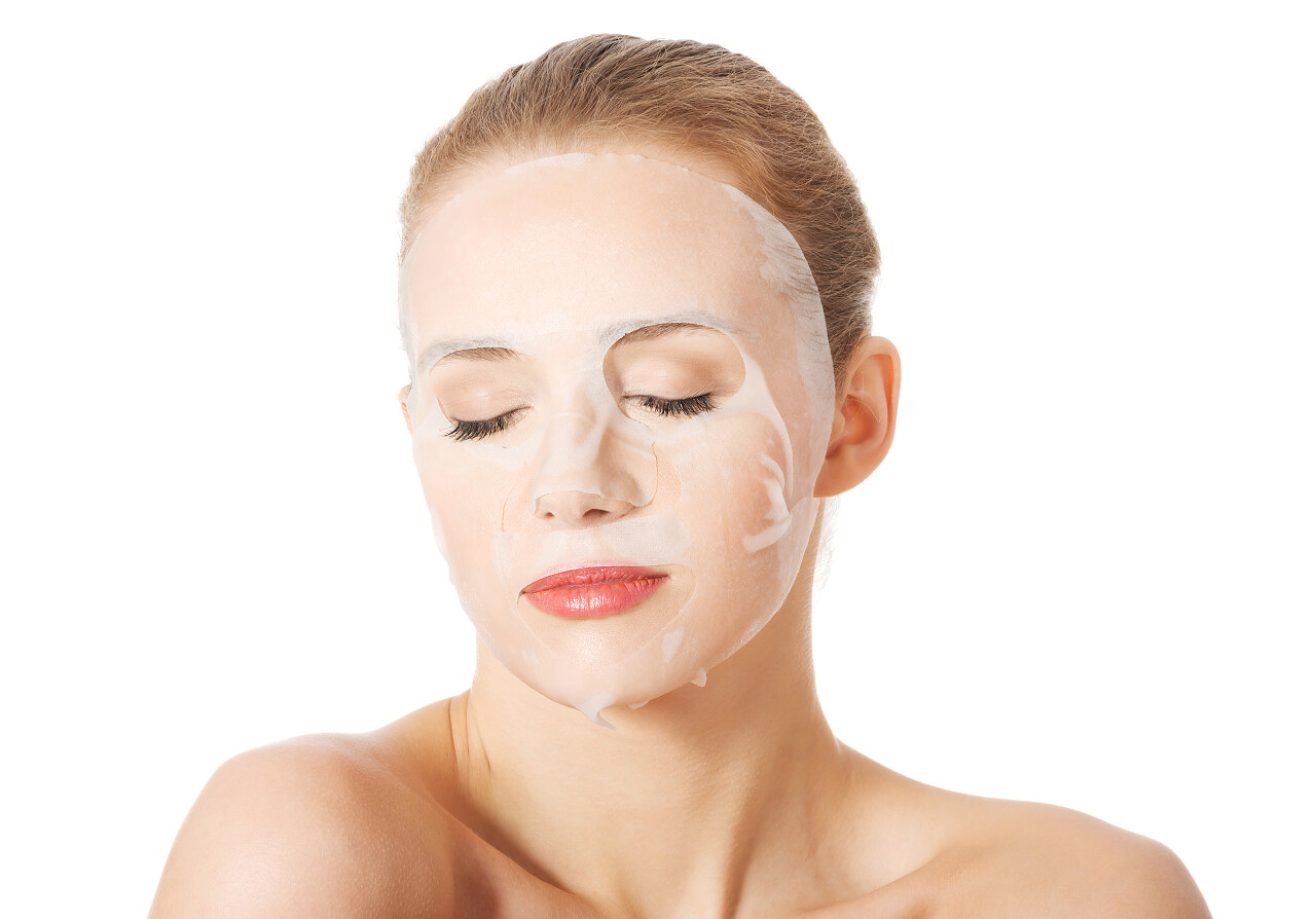 美丽的女人胶原面膜在脸上白色背景面部补水