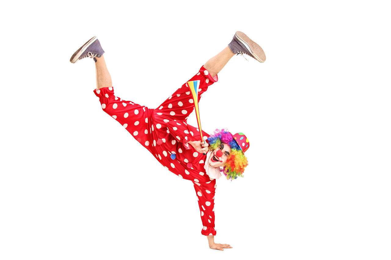 顽皮的小丑带快乐的表情在脸上 拿着隔离在白色背景上一个喇叭愚人节