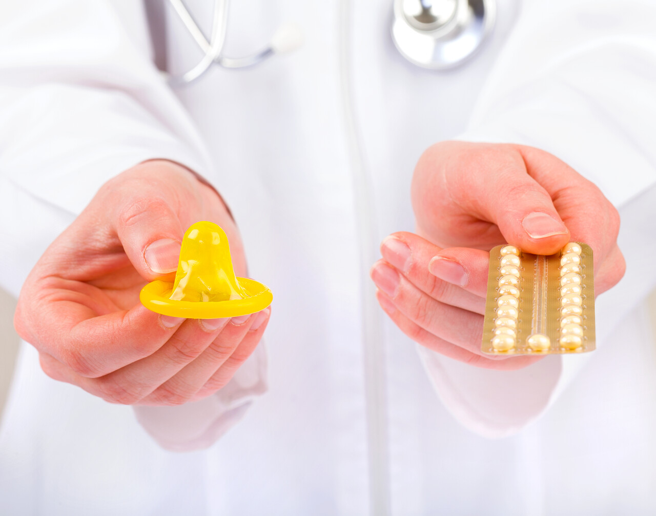 医生抱着双手避孕药和避孕套