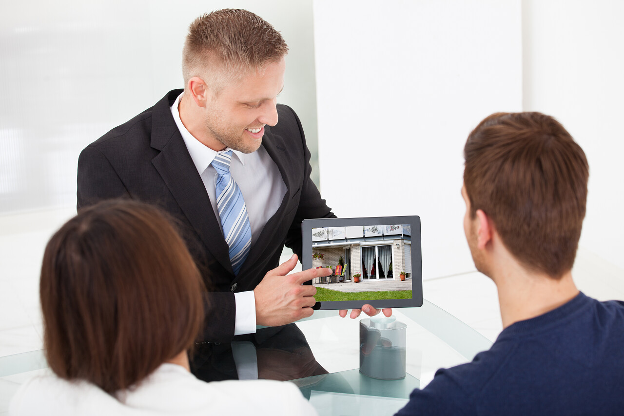 微笑顾问显示房子的以夫妇在办公台平板电脑图片