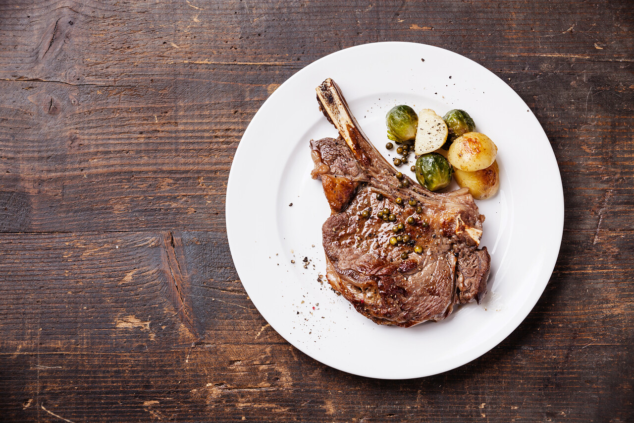 肉眼牛排配上深色的木质背景的蔬菜西餐牛排西餐背景