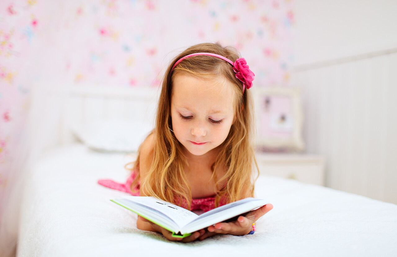 可爱的小女孩在她的房间里阅读提高专注力