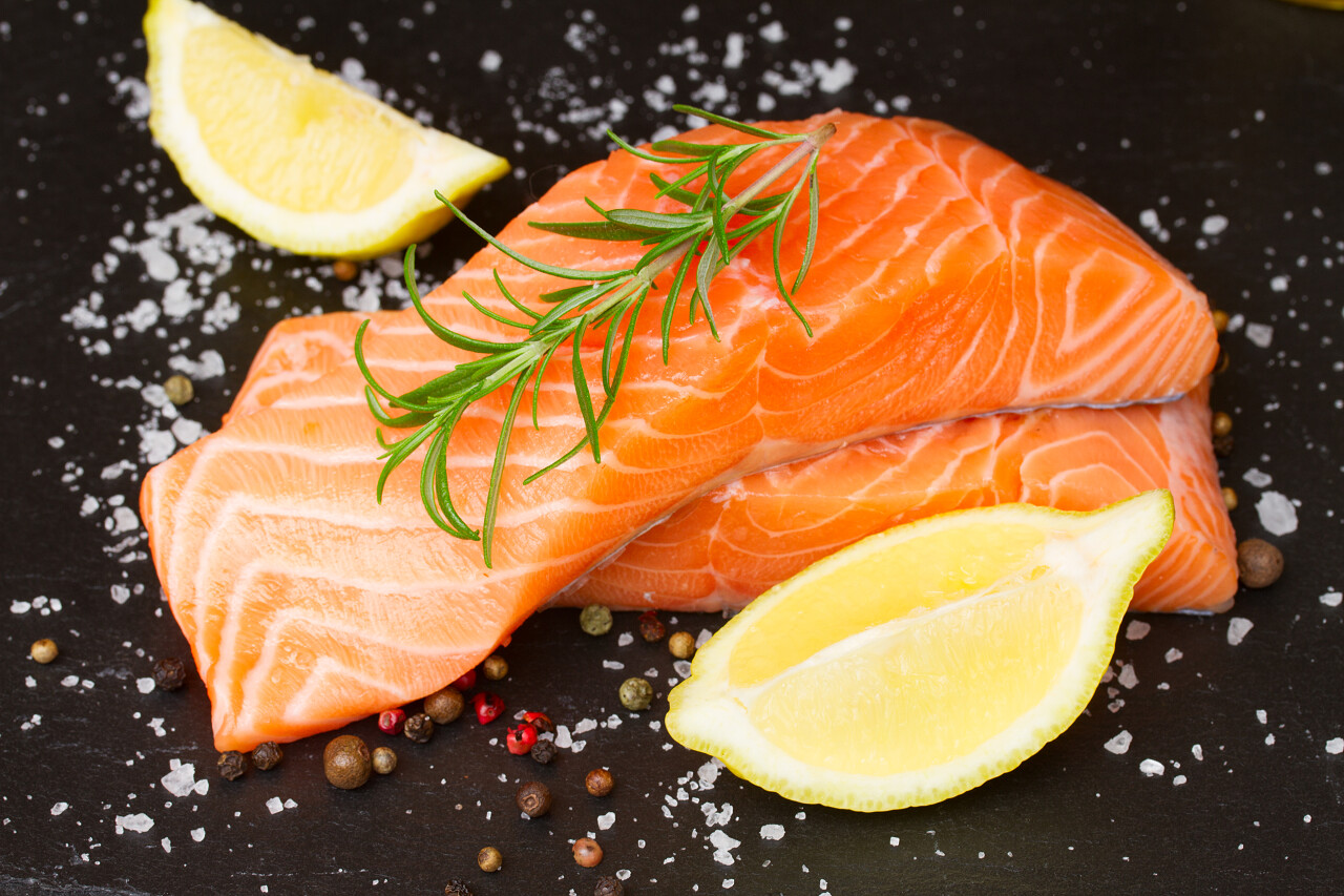 两种原料三文鱼上黑色的板子香料和柠檬