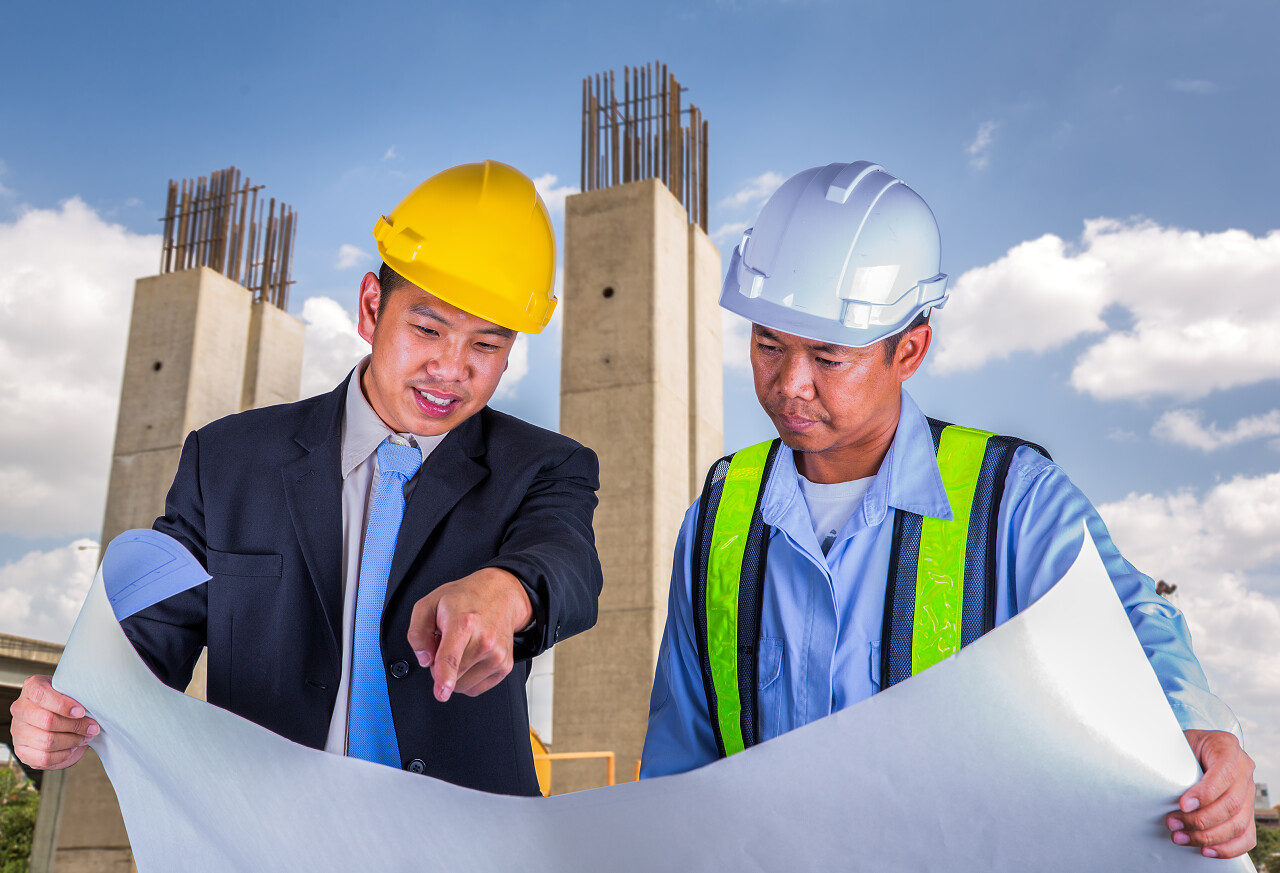 在施工现场绘制细节亚洲工程师和工人领袖