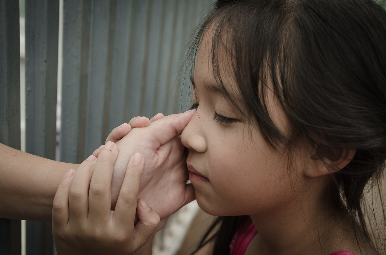 一双充满温暖的手抚摸着可爱闭着眼睛的小女孩