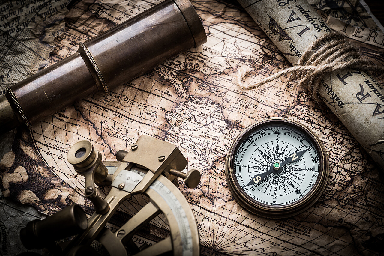破旧地图上放着指南针和望远镜