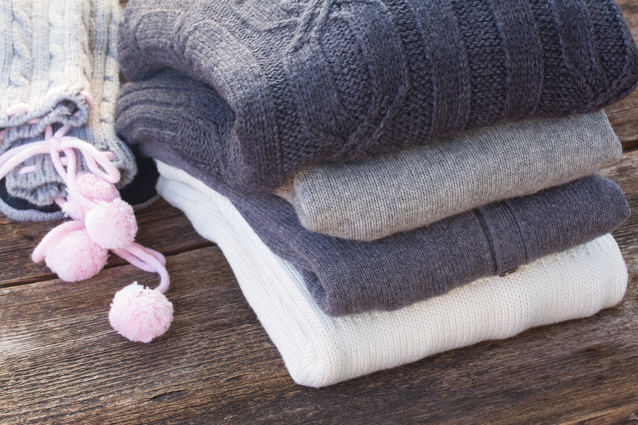 堆栈的折叠羊毛灰色和白色的衣服上木制背景