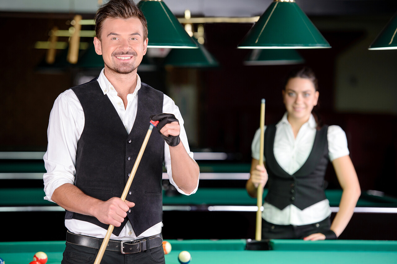 年轻的男人和女人在黑暗台球俱乐部打职业台球