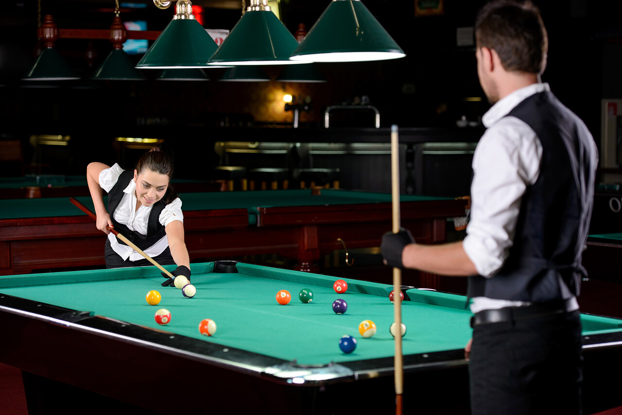 年轻的男人和女人在黑暗台球俱乐部打职业台球
