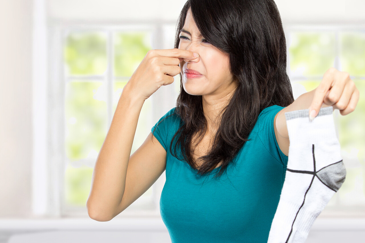 年轻女子捏着鼻子拿走袜子