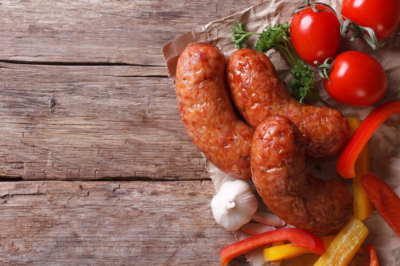 木制背景上的烤香肠和蔬菜