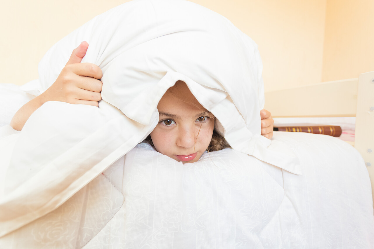 生气的女孩用枕头盖的画像