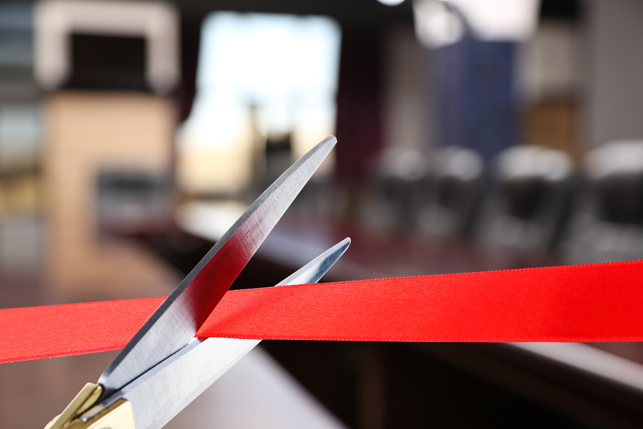 用剪刀剪开红丝带剪彩