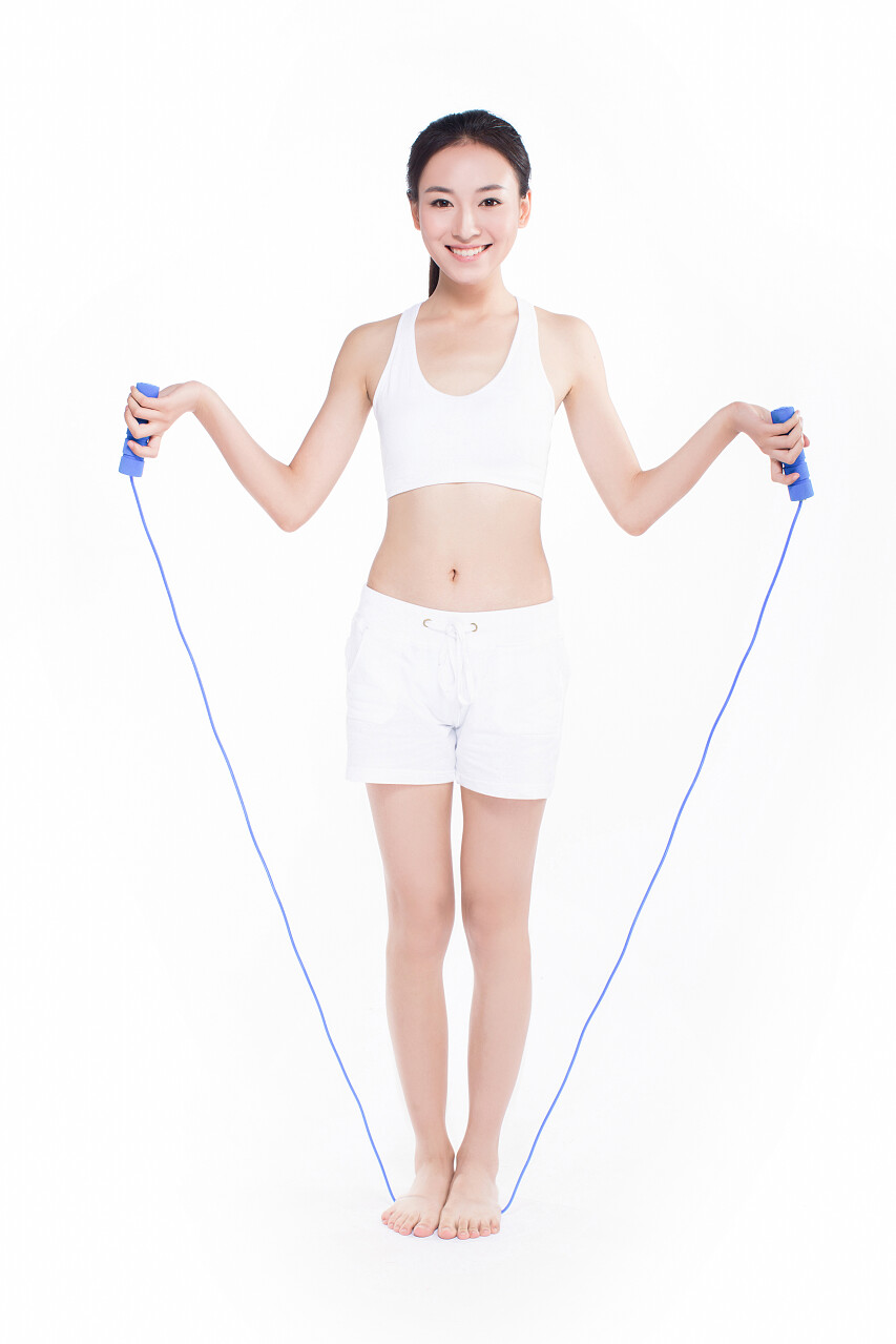 漂亮的年轻女子在健身服装跳跳绳