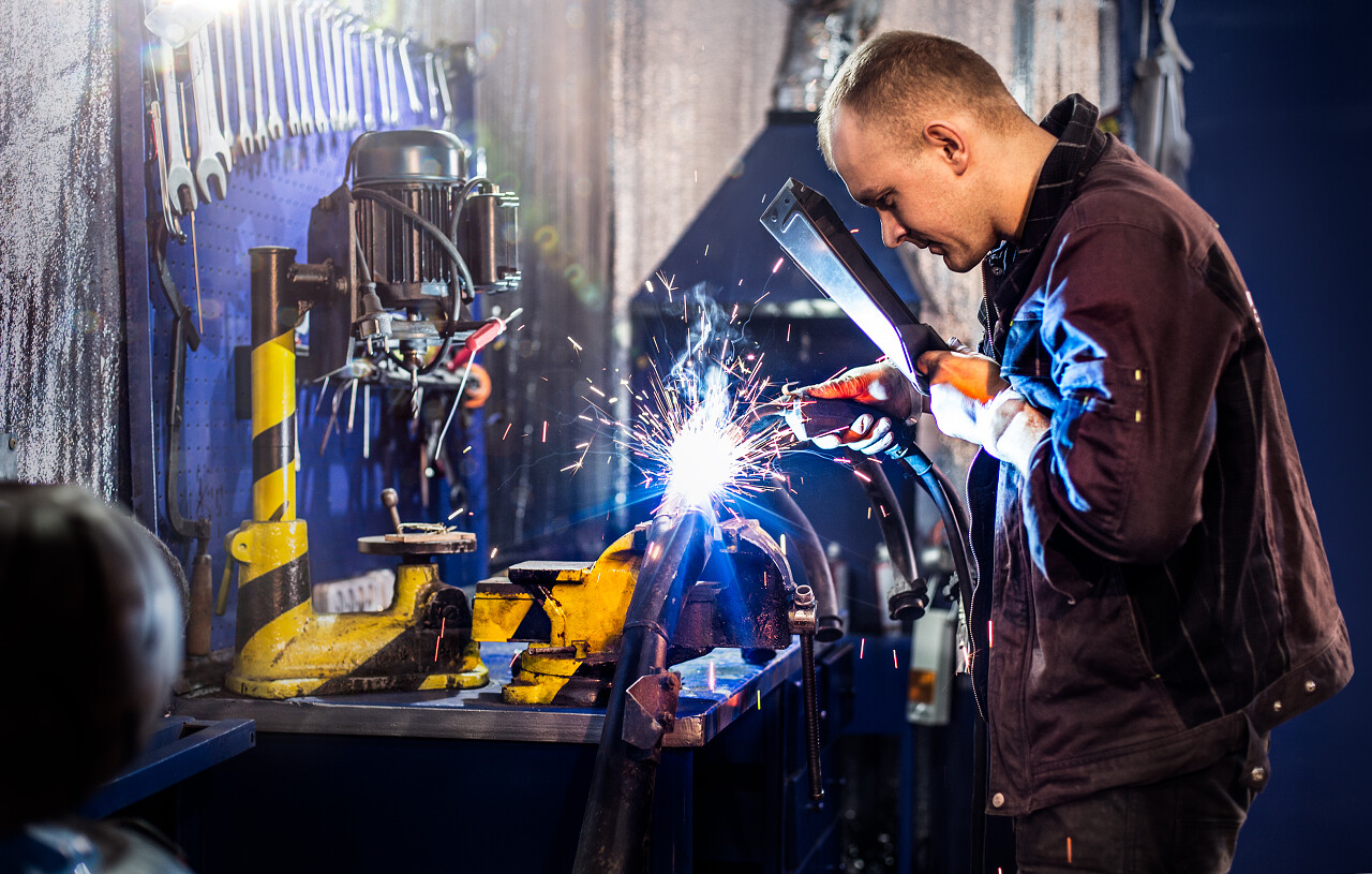 机械小心地用电弧焊接管子技术工人