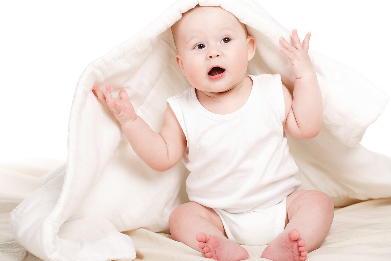 在床上有一个宝宝长着棕色的眼睛和蓬松的短发