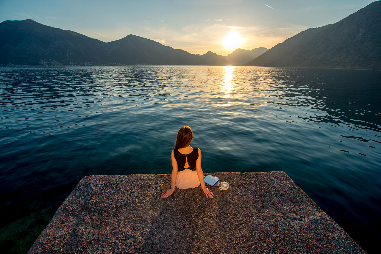 看着美丽的日出码头的美丽女人