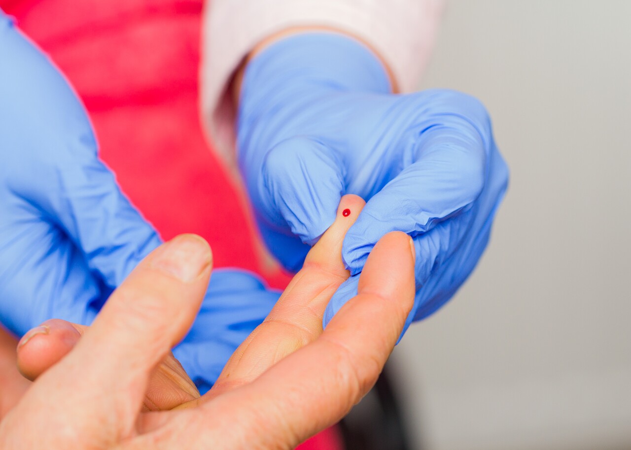 医生从老年病人身上抽取血液样本进行血糖测试