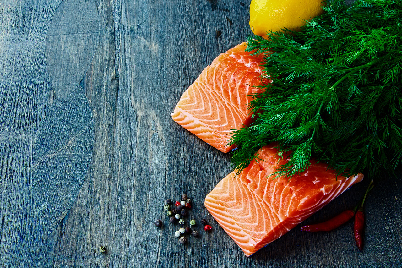 新鲜鲑鱼片与芳香草本和香料在黑暗的木制质地