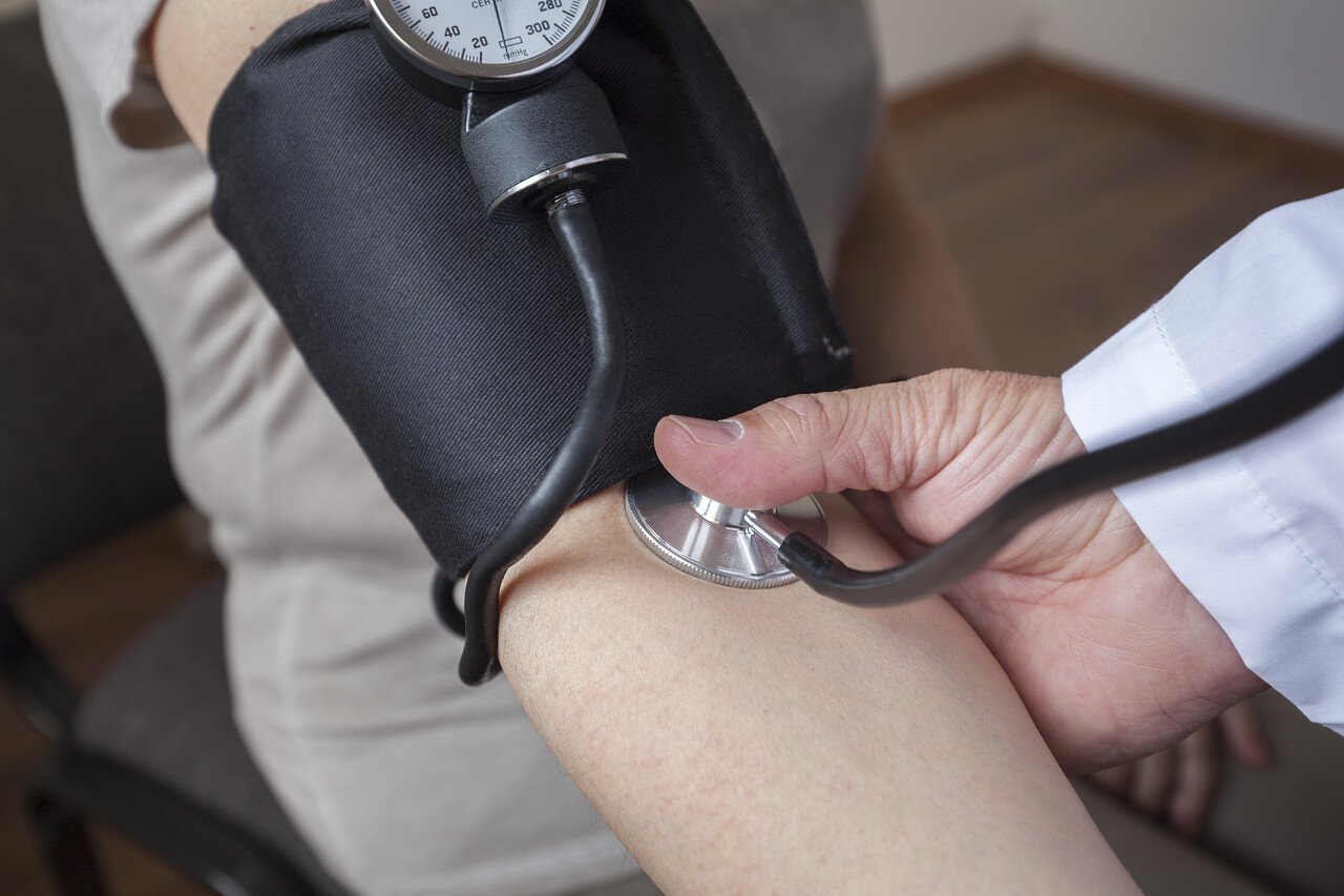 心脏病专家医生在诊室里正在给一个女人测量血压