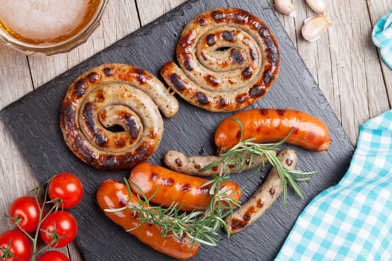 木制桌子上的烤的香肠和啤酒杯