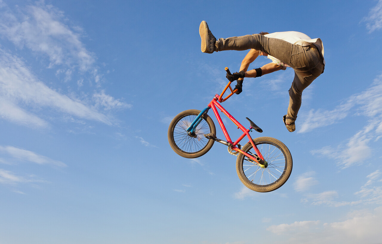 蓝色天空下一个骑着自行车跳起来的少年男孩