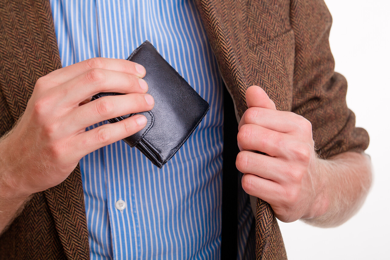 白色背景上一个男性从钱包中掏出钱支付的图片