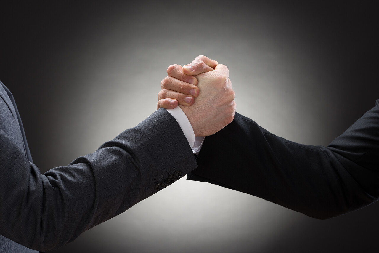 黑色背景上两个商人竞争手臂摔跤的场景竞争