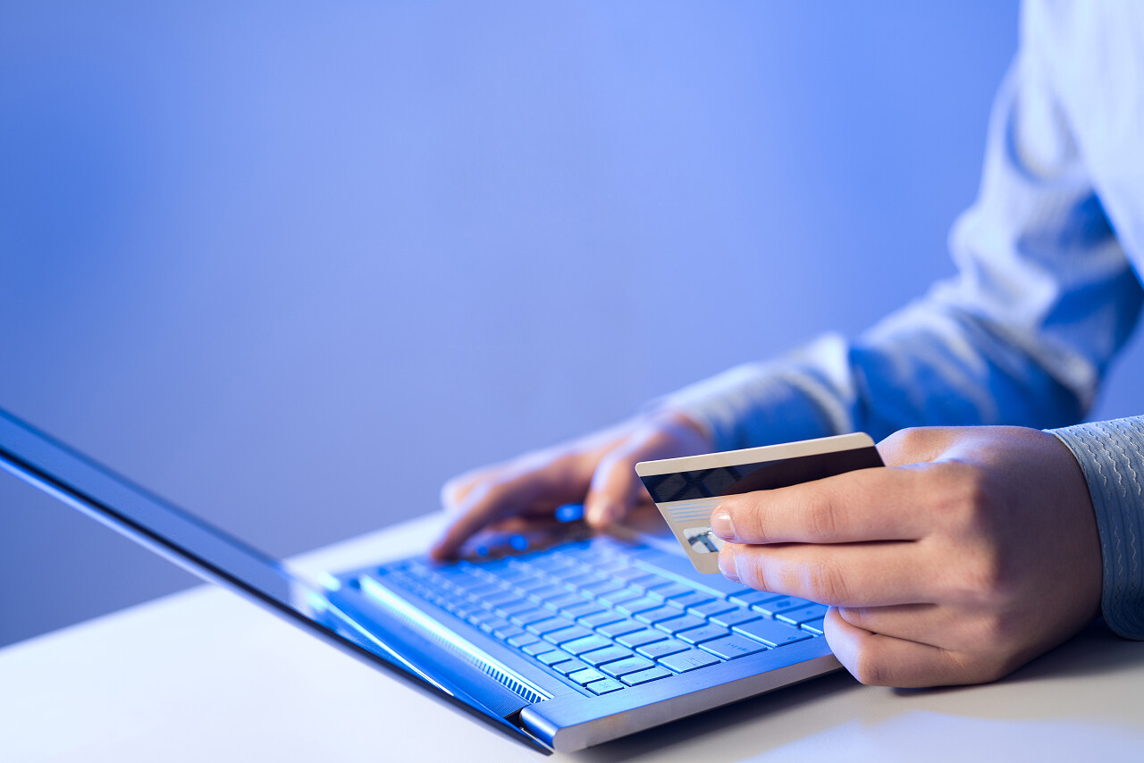蓝色背景男子使用信用卡网上支付