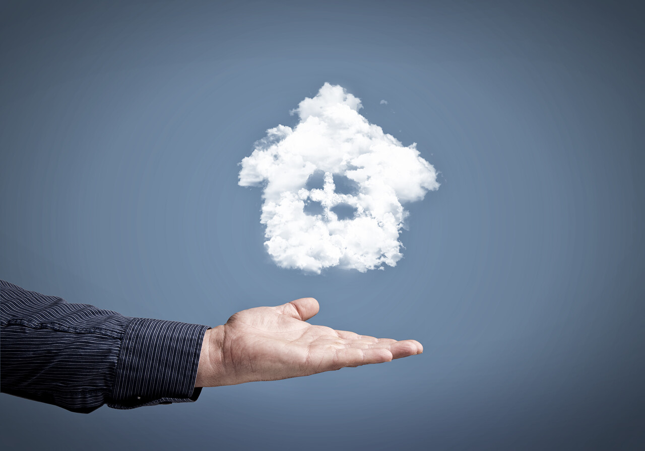 灰色背景上男性手握住云的房子