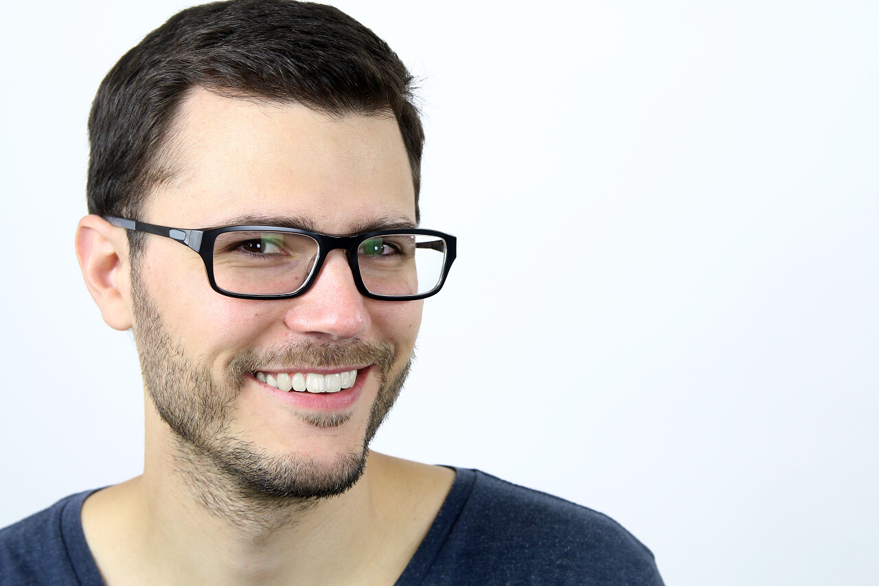 白色背景前戴眼镜年轻男子微笑的图片