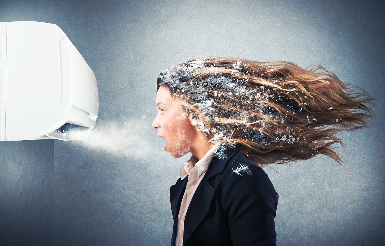 灰色背景前一个强大的空调冷冻的女孩