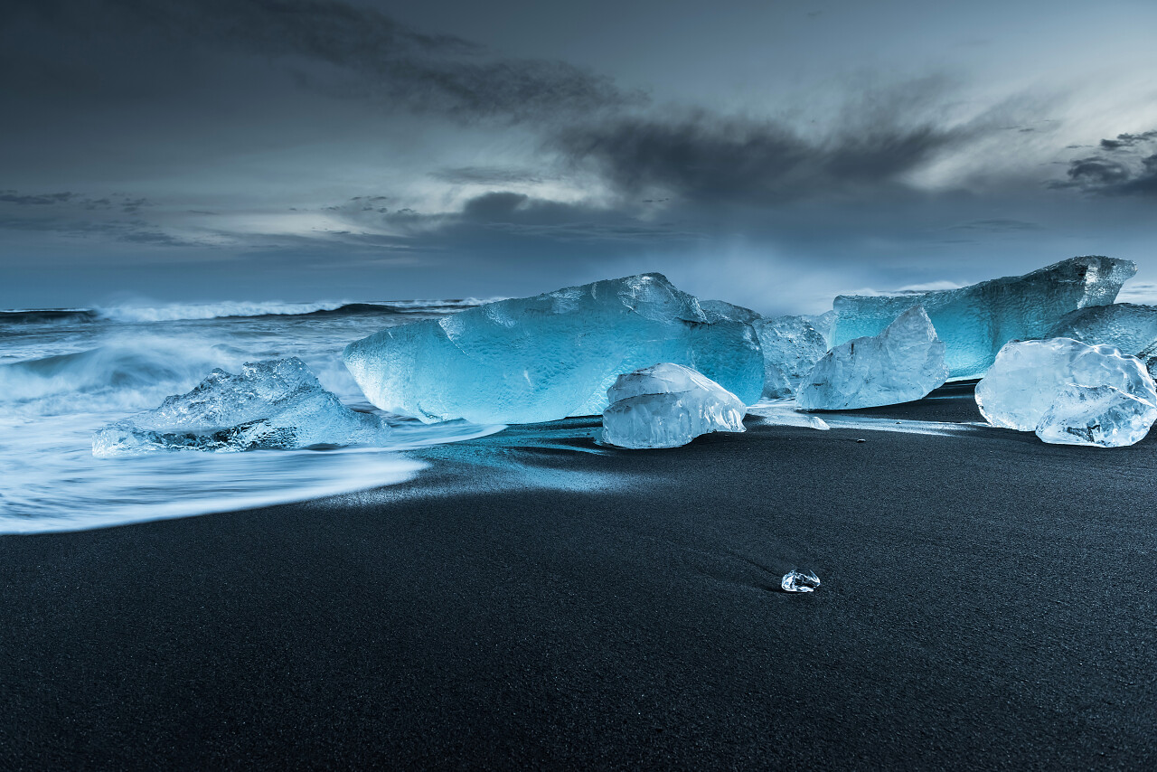灰色天空下水晶冰山在南冰岛的黑色沙滩上