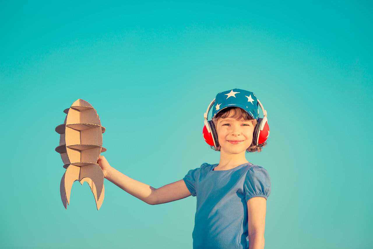 夏天蓝色天空玩火箭玩具的快乐男孩子