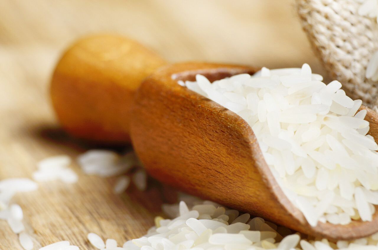 褐色木质桌子上麻布袋和一勺有机稻粒