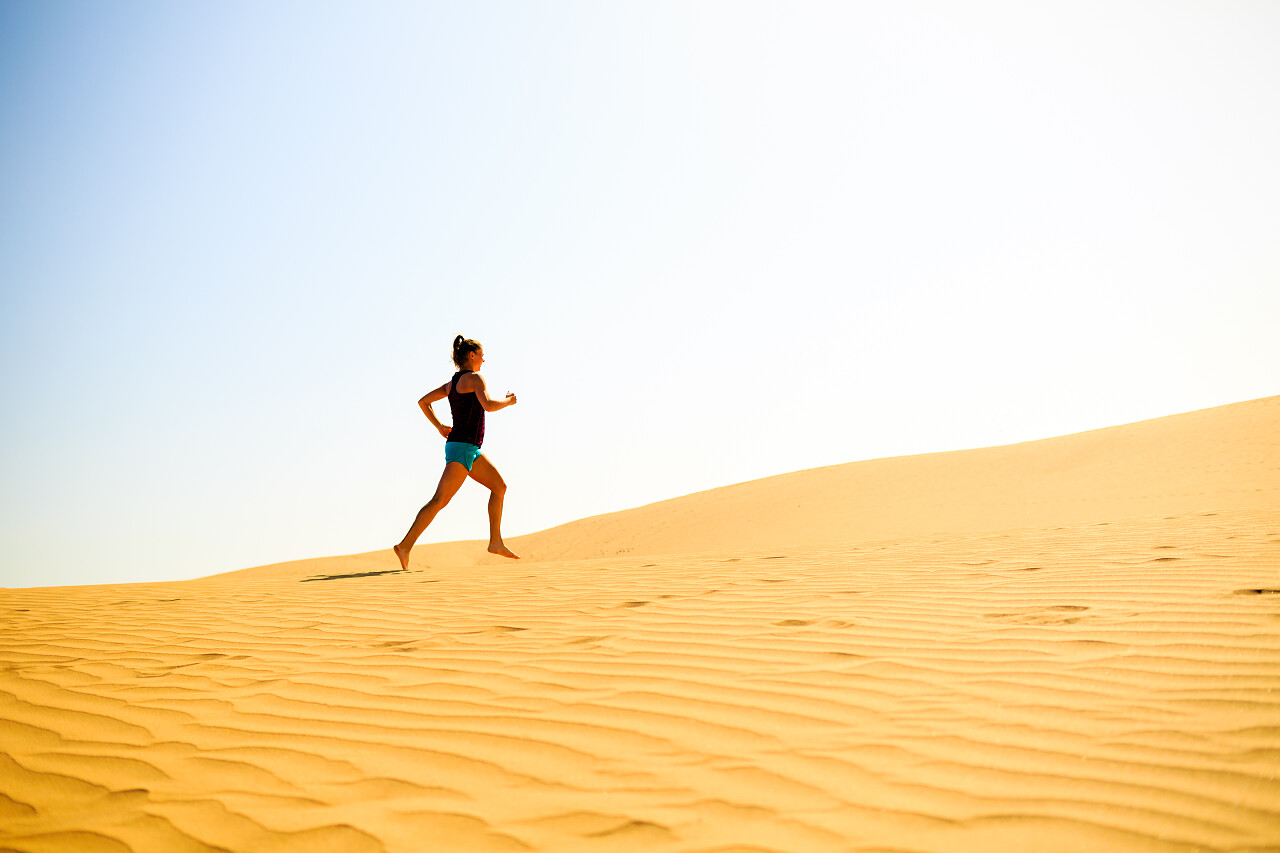 阳光灿烂夏天沙漠沙丘美丽的女子赛跑运动员慢跑克服困难