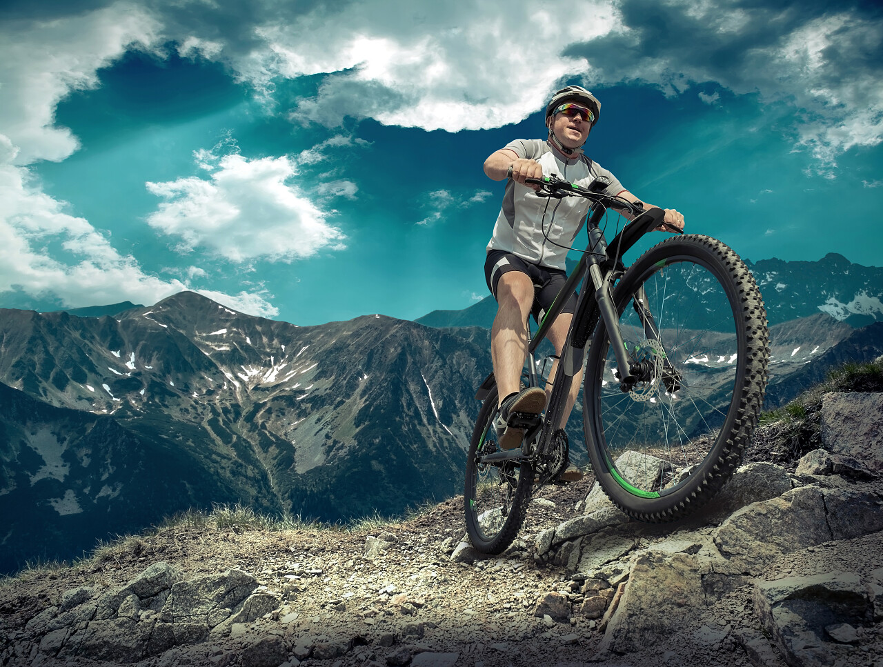 蓝绿色天空下骑着自行车四处闲逛的男人励志努力坚持不懈克服困难