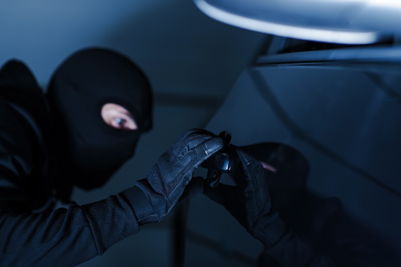深蓝色使用专业工具试图打开车的偷车贼