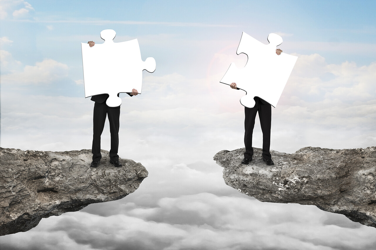 云景阳光和悬崖间两个商人拿着白色的拼图团队协作团队合作团队拼图